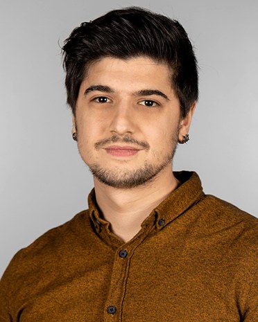 Portrait of Ertan Ağaoğlu in a mustard shirt against a gray background